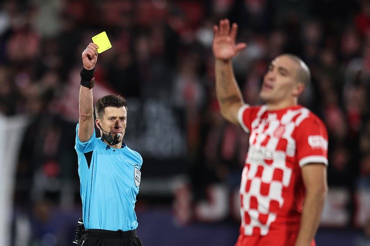 Referee Benoit Bastien shows a yellow card to Oriol Romeu of Girona FC during the UEFA Champions League 2024/25 League Phase MD6 match between Girona FC and Liverpool FC at Montilivi Stadium on December 10, 2024 in Girona, Spain.